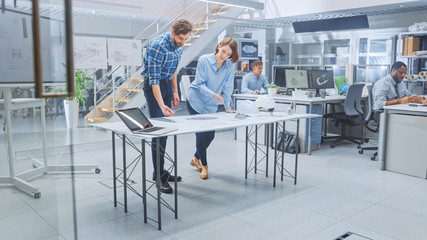 In the Busy Engineering Facility: Diverse Group of Engineers, Technicians, Working on Design for Industrial Engine Prototype. Specialists Talk During Meetings, Work with Drawings, Use Computers
