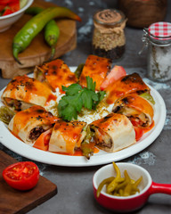 Beyti kebab rolls served in flatbread with roasted vegetables and tomato sauce