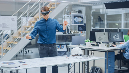 Engineering Software Developer Wearing Virtual Reality Headset Uses Gestures to Interact with Augmented Reality while Designing Industrial Engine Model in Modern Facility. AR Mock-up Concept