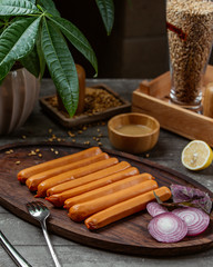 Boiled sausages decorated with red onion and lemon on wooden platter