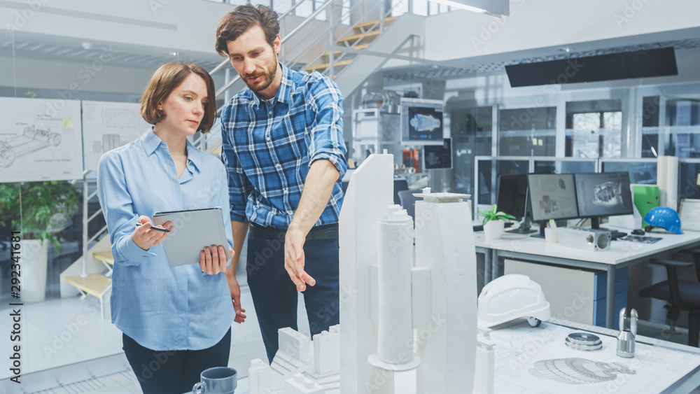 Poster in architectural bureau: architect and engineer talking, using digital tablet computer, working on a