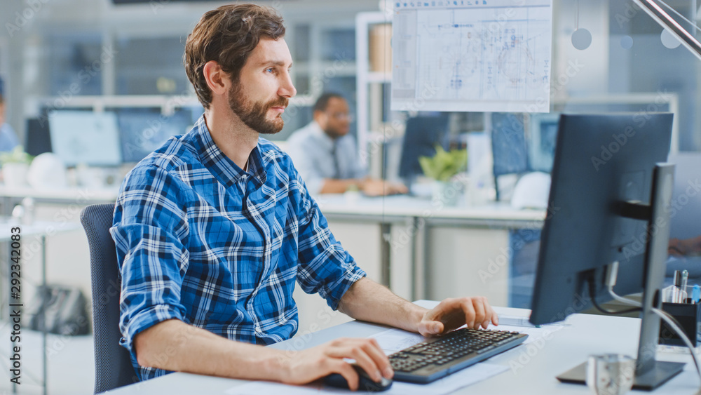 Poster In the Industrial Engineering Facility: Portrait of the Handsome Smart Male Engineer Working on a Desktop Computer. In the Background Specialists and Technicians Working with Drafts and Drawings