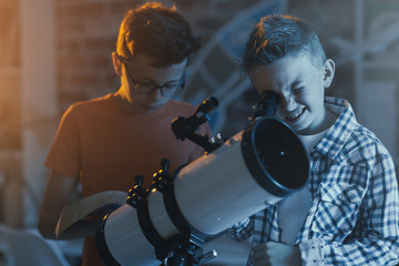 Smart kids using a telescope and stargazing - obrazy, fototapety, plakaty