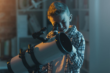 Cute boy watching stars through a telescope