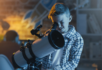 Cute boy watching stars through a telescope