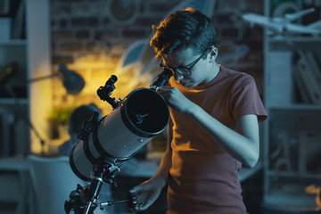 Smart boy using a telescope and watching stars