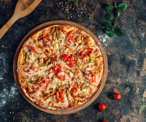 Chicken pizza with bell peppers, tomato, cheese on round wooden board