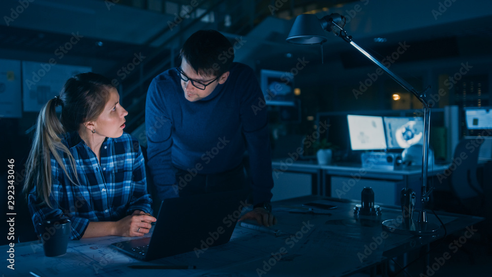 Poster Industrial Engineering Facility: Female Engineer Working on Desktop Computer, Project Manager Stands Beside and Explains Specifics of the Task and Project Details. Working Late on Engine Prototype