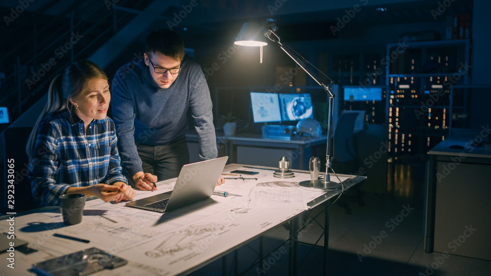 Poster Industrial Engineering Facility: Female Engineer Working on Desktop Computer, Project Manager Stands Beside and Explains Specifics of the Task and Project Details. Working Late on Engine Prototype