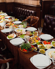 Dinner setup for guests with roasted fish, meat plate, salads, side dishes