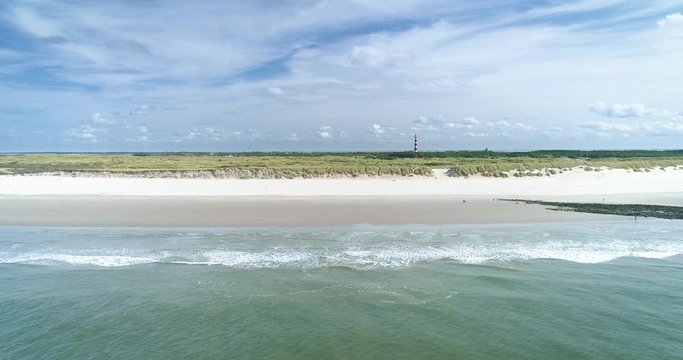 Flying Over the Dutch Island Ameland, The Netherlands. In shot are: the Lighthouse, Trees, Large Fields of Dunes, North Sea, Blue Sky, Clouds. 4K Drone Footage.