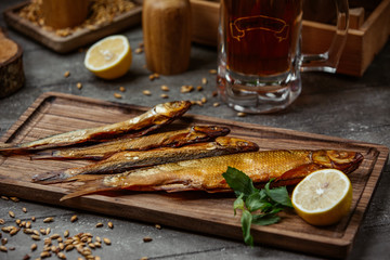 Dried smoked fish served with lemon on wooden board for beer night