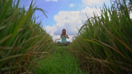 Slowmotion steadicam shot of a young woman doing meditation for Muladhara chakra in a Balinese way