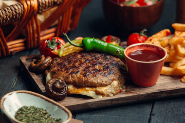 Grilled bbq steak sandwich with cheese and vegetables together with french fries