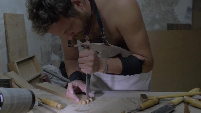 a carpenter carves a dovetail on a wooden part with a chisel, on a workbench. woodworker processes a wooden board. 4k. 4k video. 60 fps