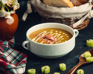 Pumpkin soup with grilled chicken pieces decorated with cellery stick slices