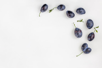 Ripe blue plum pattern on white. Fruit background with copy space. Top view, flat lay.