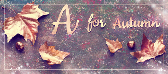 Autumn flat lay with painted golden leaves and text 