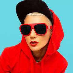 Fashion tomboy girl in red sweatshirt hoodie and sunglasses street urban style