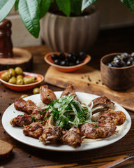 A plate of lamb entrecote ribs kebab with onions and greens