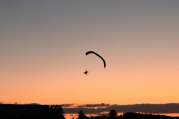 Fototapeta na wymiar Silhouette of the hang glider that flying in the sky