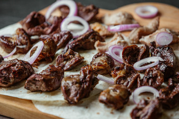 Close up of grilled tikka kebab on flatbreads with red onion slices