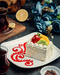Small white creamy cake decorated with strawberry, orange, kiwi