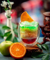 Three colors exotic cocktail with apple and orange juice and ice shaving