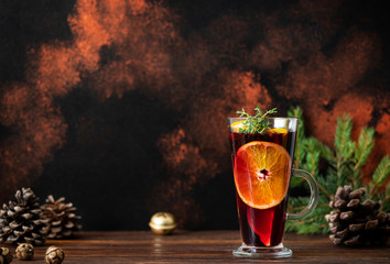 Mulled wine is a warm drink made from red wine, citruses, fruits and spices in a glass on a wooden...