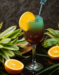 Two-colour cocktail in wine glass decorated with orange and stirrer