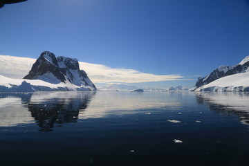 spokojne zimne wody pomiędzy ośnieżonych skałami u wybrzeży antarktydy w piękny słoneczny dzień - obrazy, fototapety, plakaty