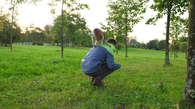 Sportive dog perform trick, jump on back of man sitting squat on haunches. Active beagle show agility and trained skills, easy spring up on owner shoulders