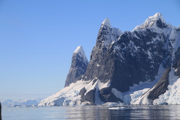 spokojne zimne wody pomiędzy ośnieżonymi skałami u wybrzeży antarktydy w piękny słoneczny dzień - obrazy, fototapety, plakaty