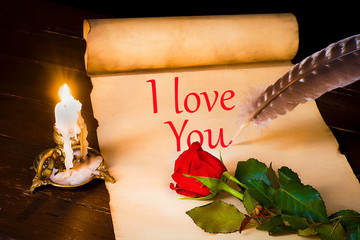A scroll of parchment with the words I Love You, a feather and a lit candle