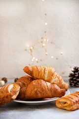 Festive Christmas or New Year pastries, sweet croissants, Christmas sweets. Christmas mood. Christmas lights. Winter Holidays Concept. Light background. Selective focus