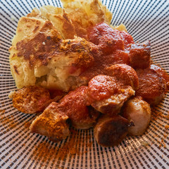 potato gratin with crispy brown crust on a hot german currywurst with red sauce