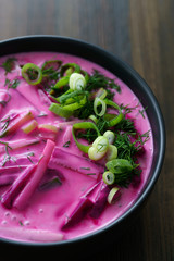 Lithuanian Saltibarsciai (Cold Beet Soup) seasoned with spring onions and dill. Dark wooden table, high resolution