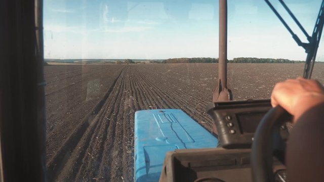 Farmer driving tractor in cultivating field. Agricultural works at tractor.