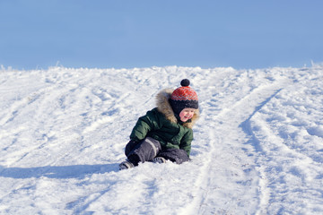 Fototapeta na wymiar Cheerful boy riding a snowy mountain in winter