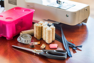 Fototapeta na wymiar Bobbins, scissors, tape measure and a sewing machine
