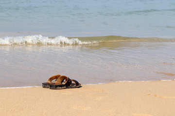 Sandals on the sandy beach. Concept of summer holidays and swimming in the sea in a sunny day