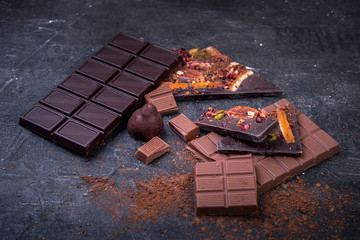 Pieces of dark and milk chocolate and cocoa on a dark background.