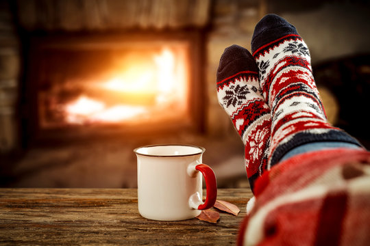 Woman legs with christmas wool socks and fireplace 