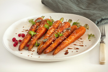 Baked organic carrots with honey, parsley, cheese and flax, pumpkin, sunflower seed on plarte. Organic vegan food.