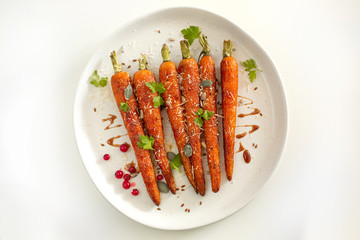 Baked organic carrots with honey, parsley, cheese and flax, pumpkin, sunflower seed on plarte. Top view. Organic vegan food.