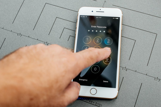 PARIS, FRANCE - SEP 26, 2016: Male hand holding New Apple iPhone 7 8 Plus smartphone after unboxing and testing by installing the app application software Enter passcode secret code