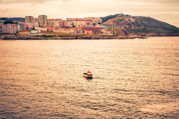 Obraz premium Small fishing boat fishing in the Atlantic Ocean along the coast of Galicia at sunset. A coruña, Spain