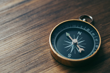 One gold compass on top of a wooden desk