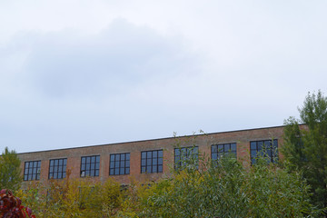 Obraz premium View through the trees on the brick house with large Windows.