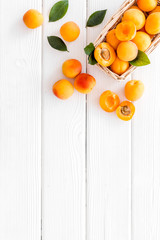 Collect apricots, white wooden background top view copy space, pattern with leaves